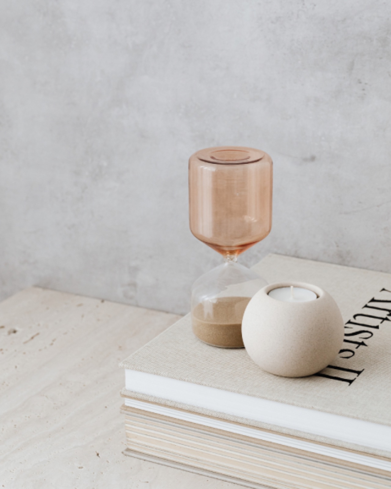 an hourglass and candle on top of a book to show interior home design by Anything but vanilla by margot in vegas